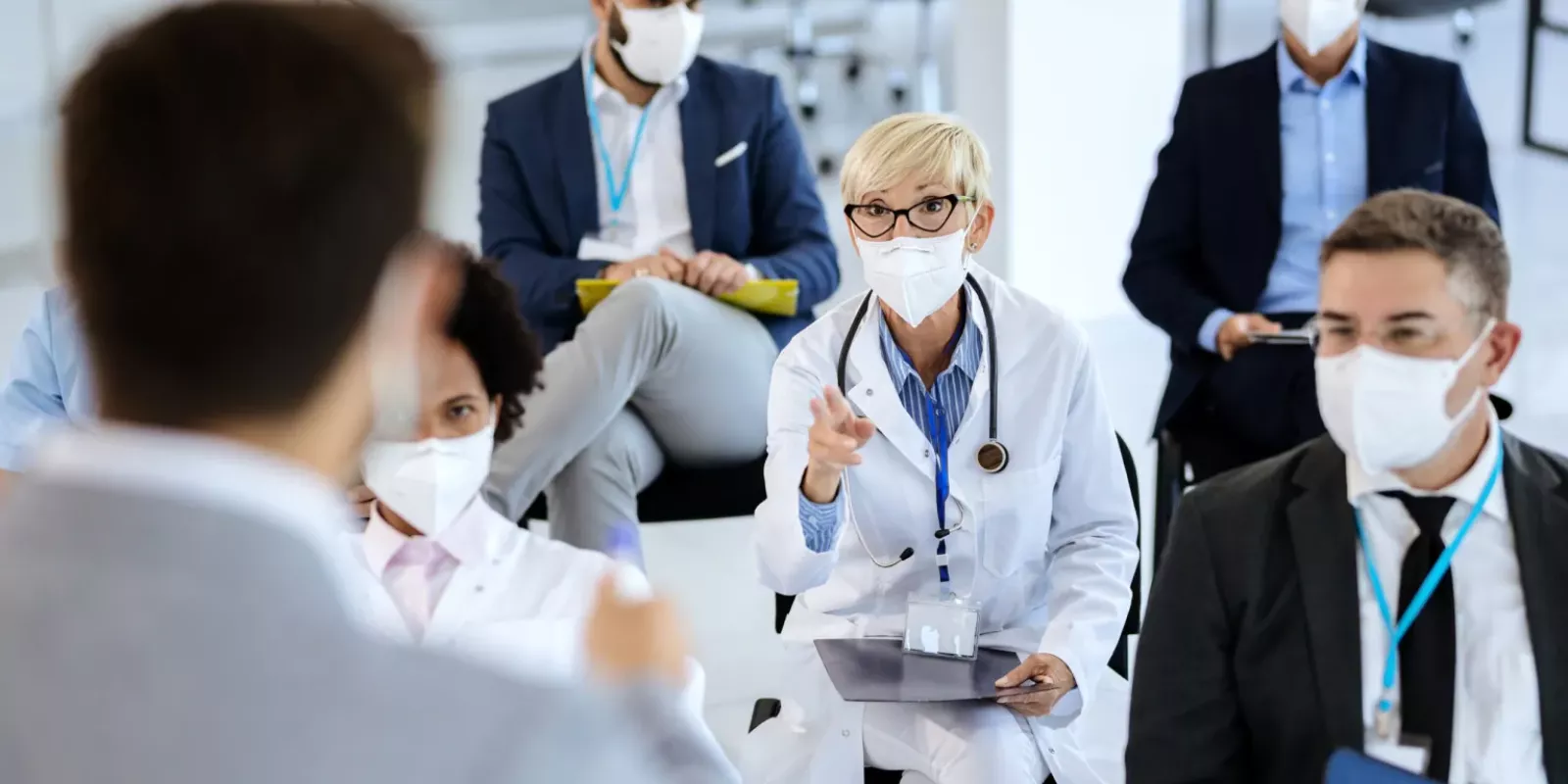 female-doctor-talking-presenter-while-attending-seminar-during-coronavirus-epidemic-scaled