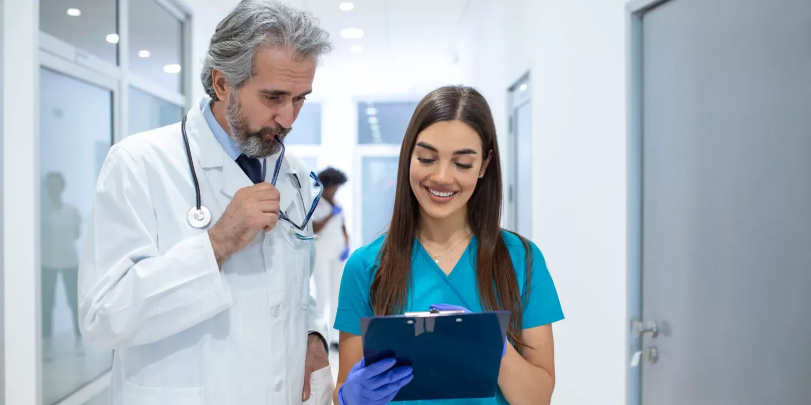 group-medics-with-clipboard-discussing-along-hospital-corridor-doctor-nurse-briefing-medical-report-2-scaled